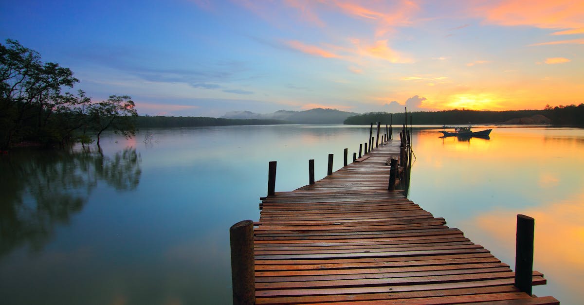 Serene sunset view over a tranquil lake with a wooden dock stretching into the distance.