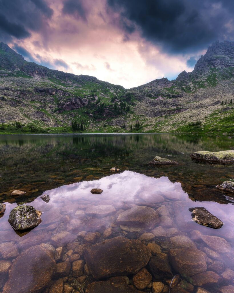 Tranquil lake with mountain reflections at sunset in Krasnoyarsk Krai, Russia.