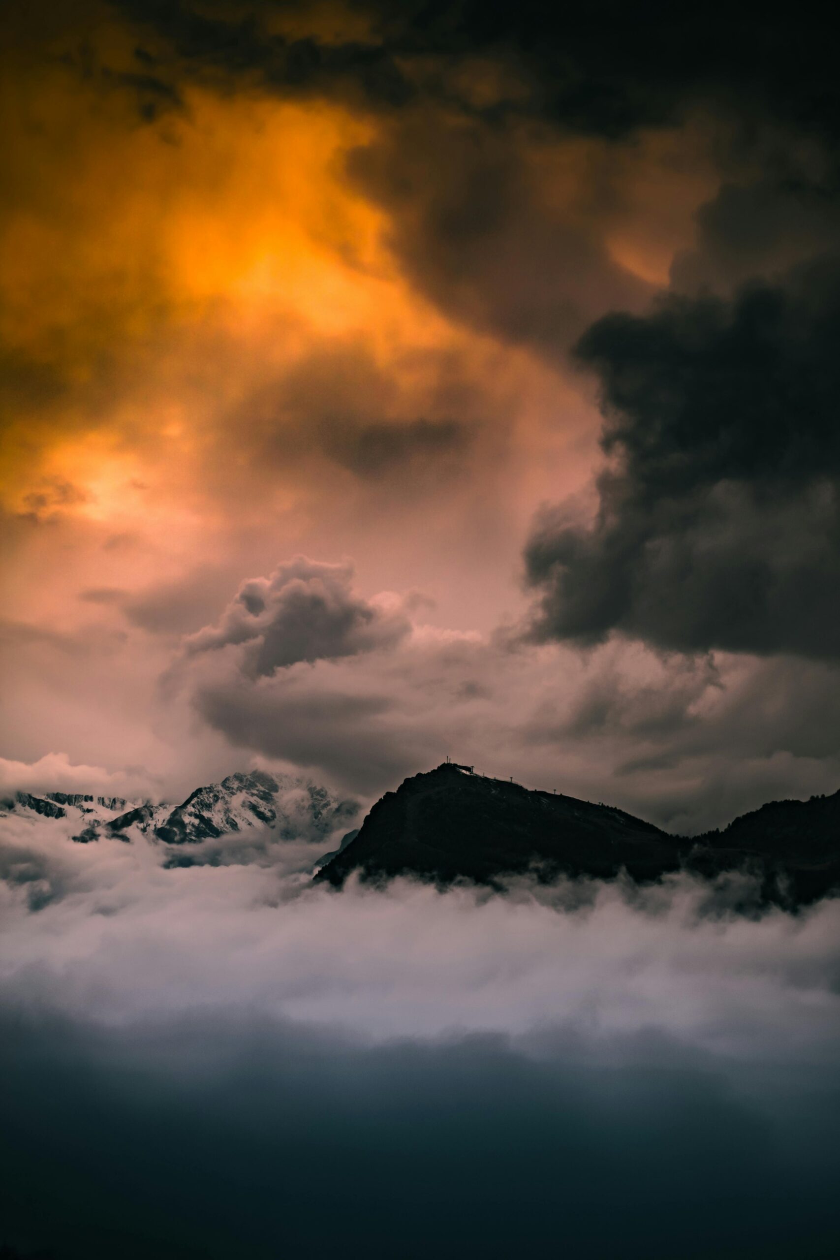 Epic scene of cloudy sunset over misty mountains in Italy, creating a dramatic atmosphere.